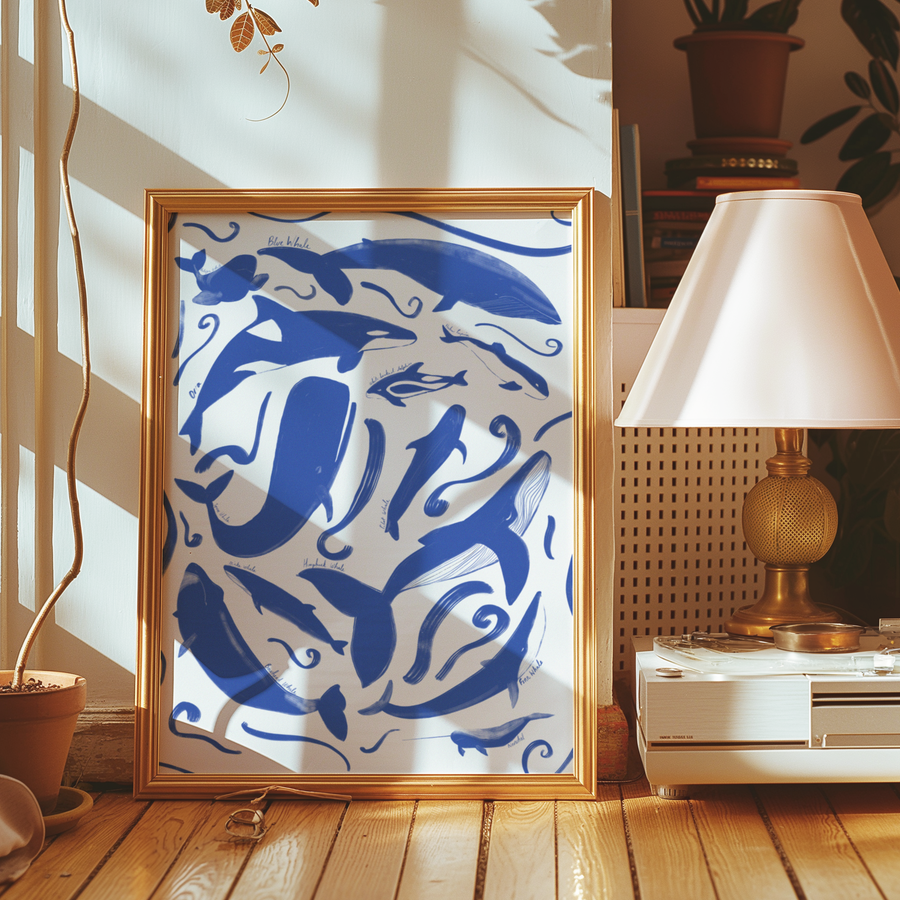 Framed artwork with blue dolphins on a white background, placed on a wooden floor.